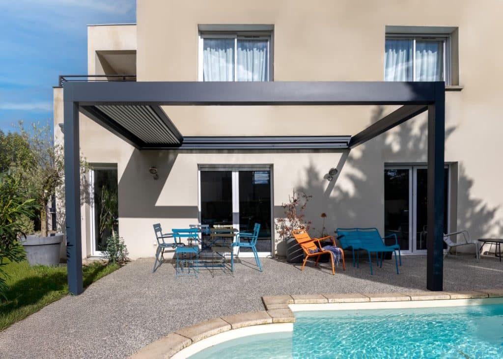 Pergola toile rétractable installée sur terrasse au bord d’une piscine