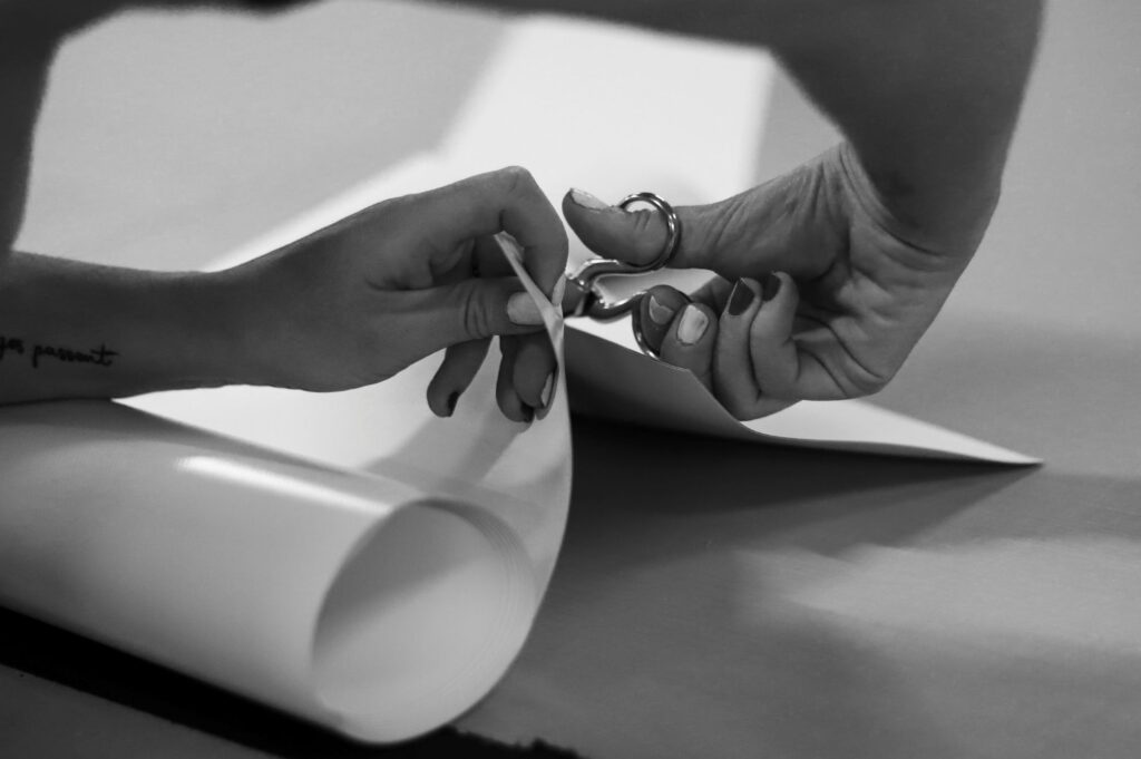 Gros plan détaillé sur le geste précis et méticuleux d’un expert Coublanc, illustrant l'attention portée à chaque détail lors de la découpe d’une toile, garantissant ainsi une installation parfaite chez le client.