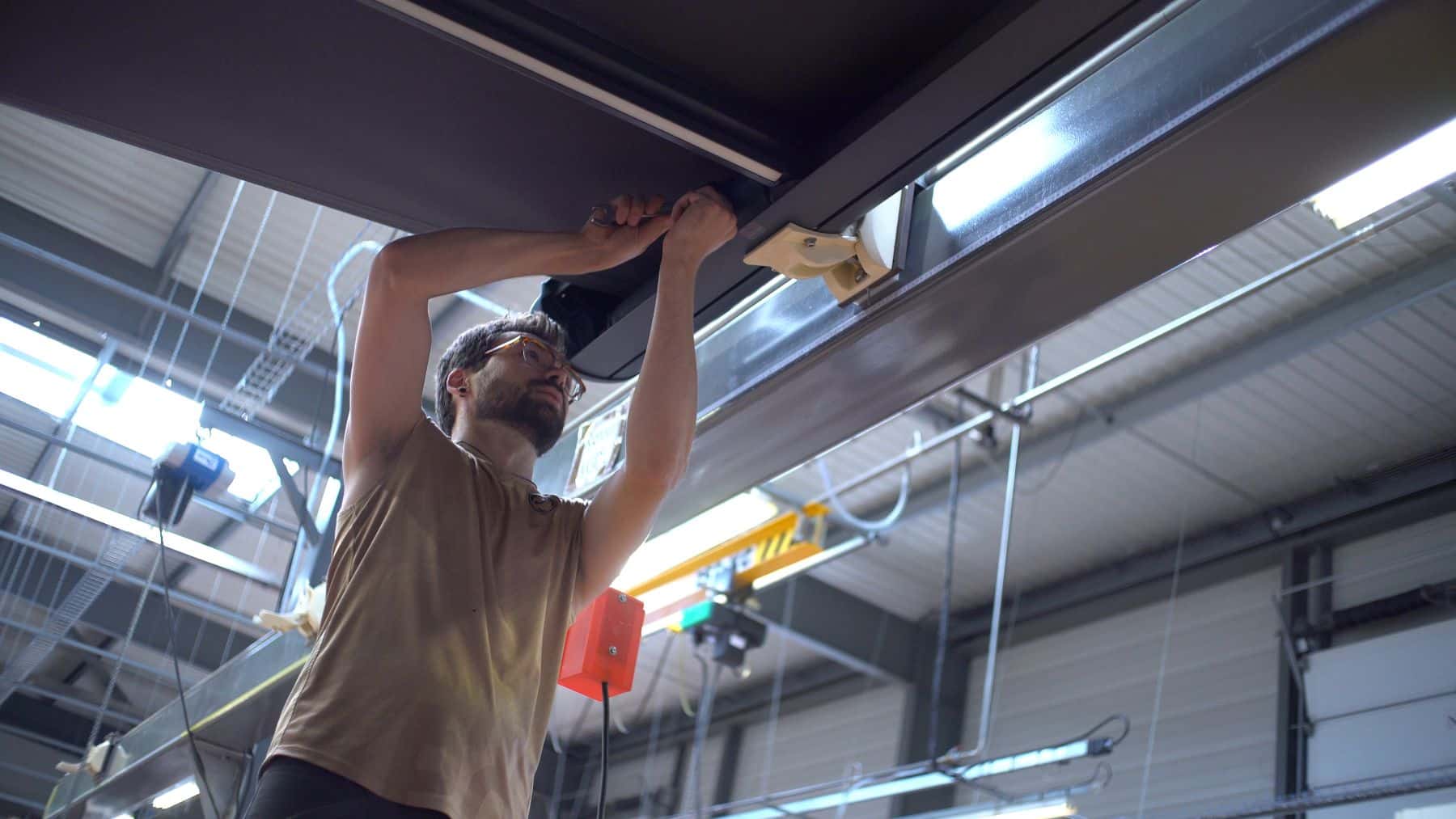 Collaborateur expert en stores effectuant un pré-réglage en atelier.