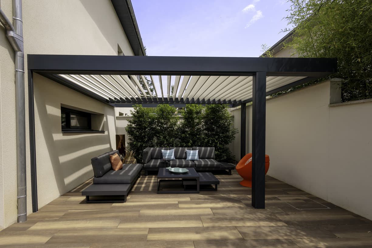 Pergola bioclimatique design installée sur une terrasse moderne avec mobilier de jardin contemporain