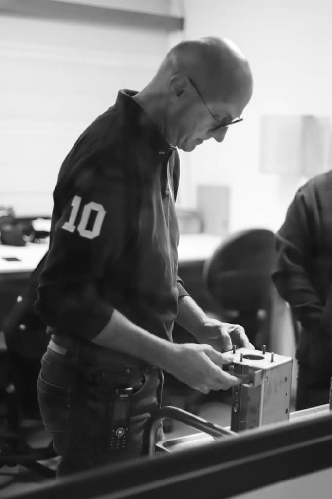 ingénieur manipulant une pièce métallique en atelier