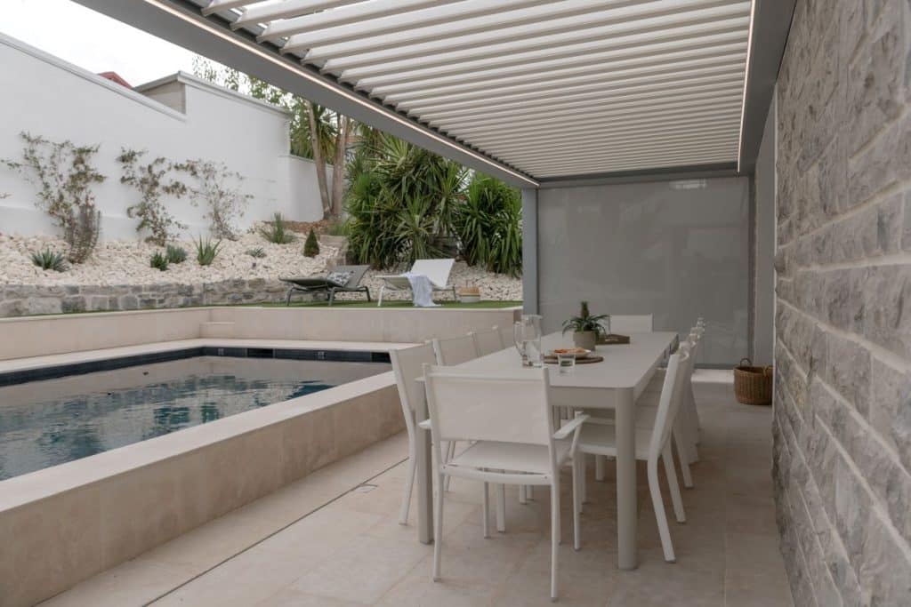 Vue intérieure d'une pergola à lames orientables blanches avec store latéral zippée fermé