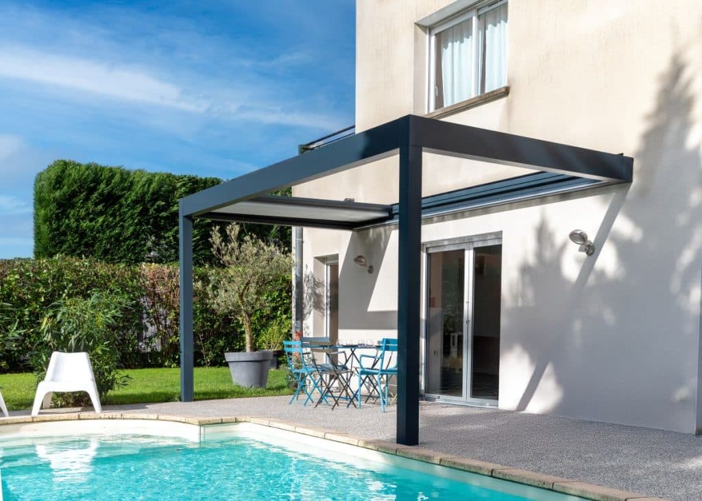 Pergola toile grise installée sur terrasse, vue depuis la piscine
