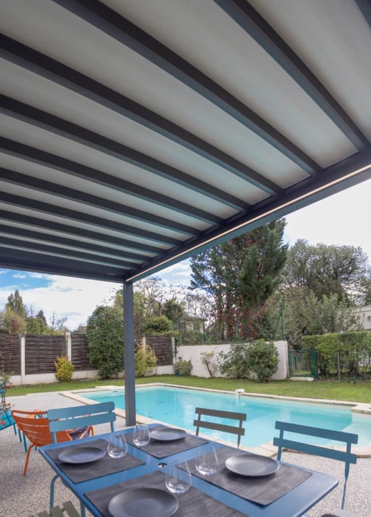 Vue latérale sous pergola toile, mobilier outdoor face à la piscine